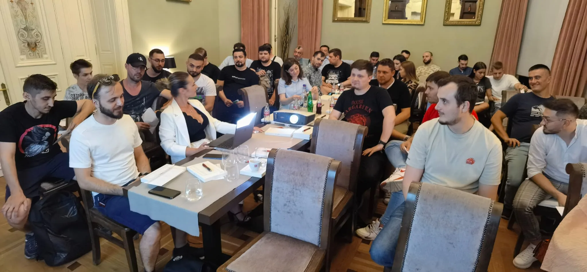 Alexa Nica, în sacou alb, facilitează un training la o masă plină de participanți implicați